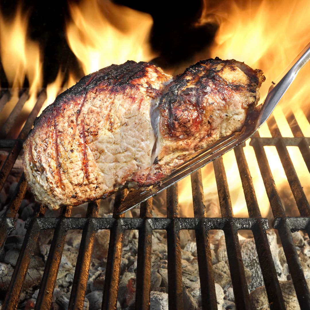 A la parrilla carne en un plato con un fuego en el antecedentes